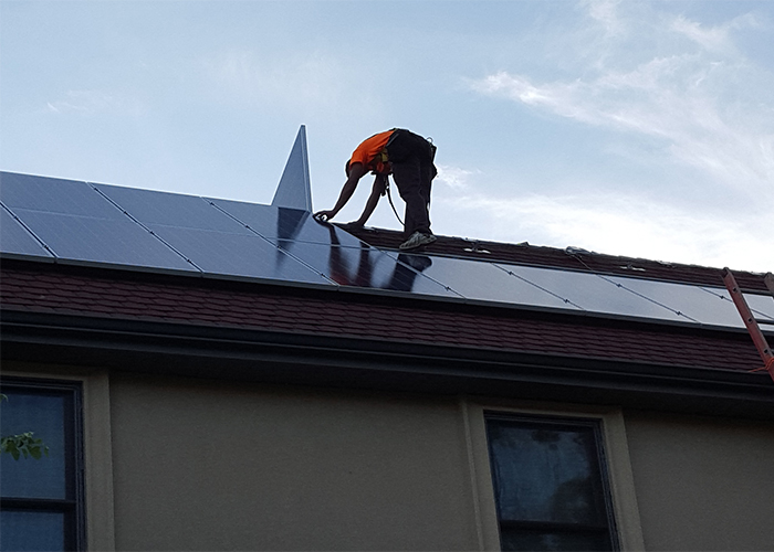 A Cerfied Trifecta Technician performing a solar panel installation on the Roof of a Home